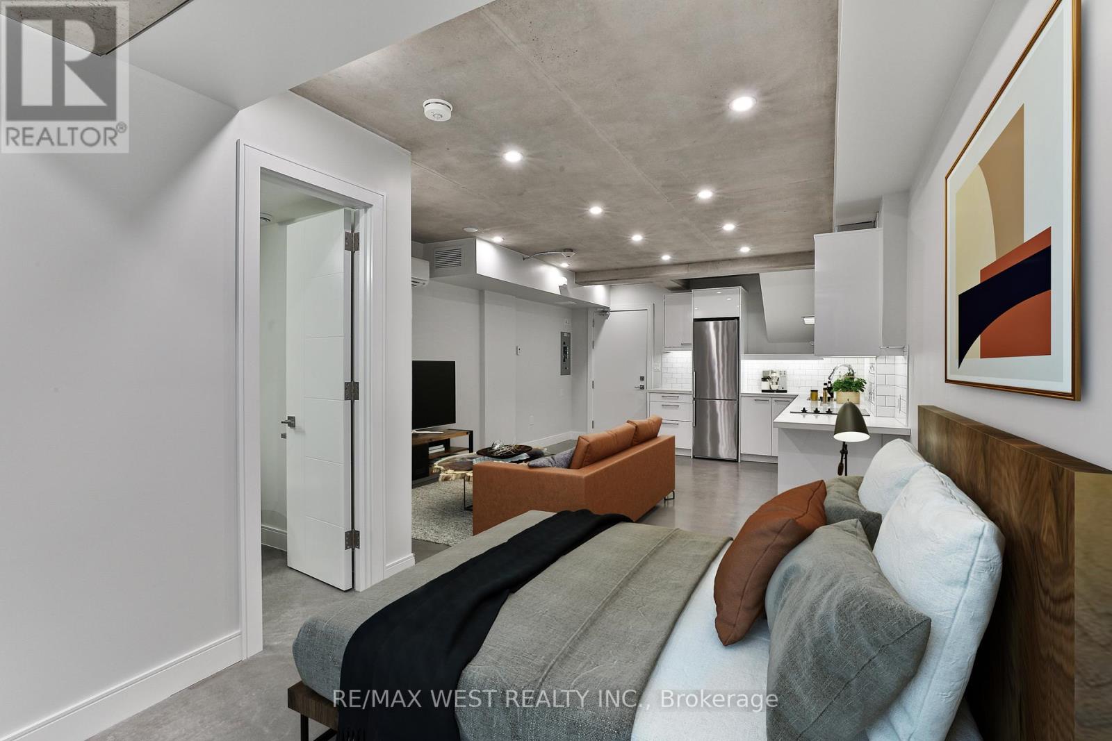 A modern living room with a grey couch and a painting on the wall.