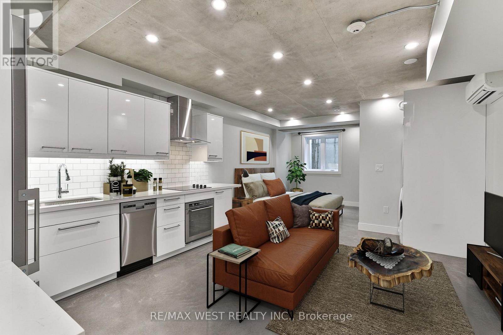 A modern kitchen with white cabinets and appliances, a brown leather sofa, and a wooden coffee table.