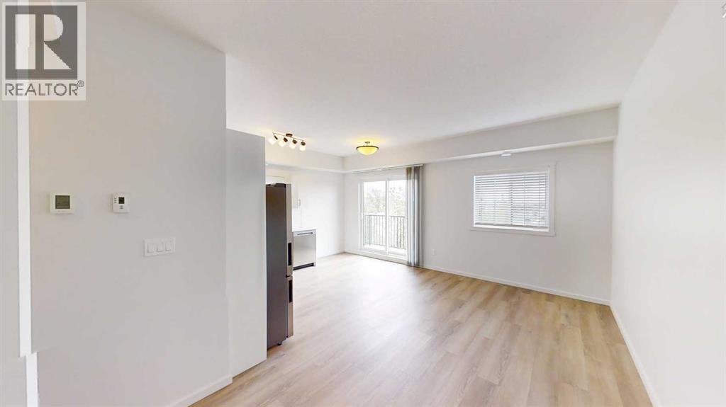 A spacious room with wooden flooring and white walls.