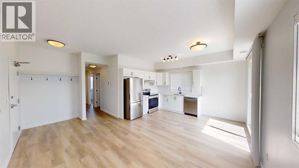 A spacious kitchen with a refrigerator, sink, and cabinets is visible in the image.