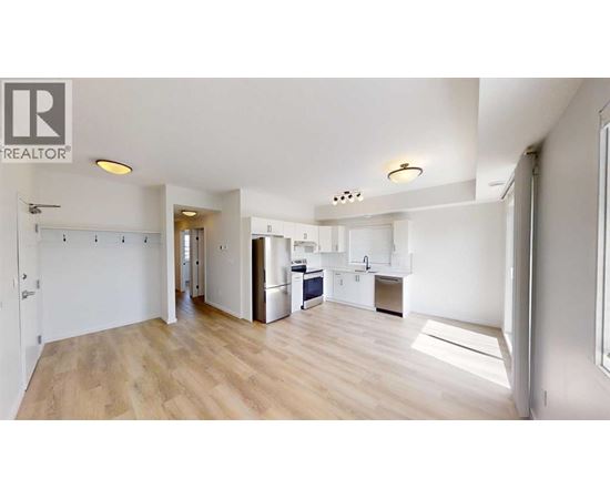 A spacious kitchen with a refrigerator, sink, and cabinets is visible in the image.