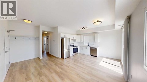 A spacious kitchen with a refrigerator, sink, and cabinets is visible in the image.
