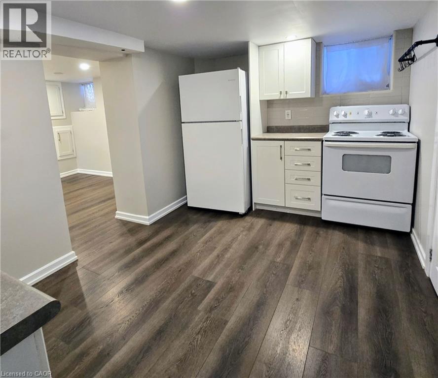 A kitchen with white appliances and wood flooring.