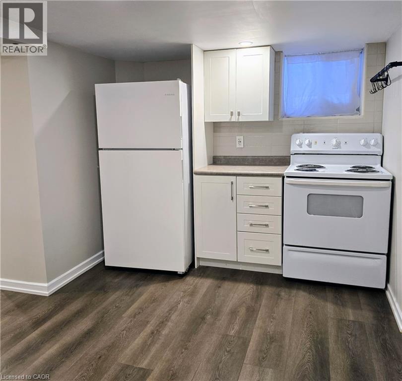 A white refrigerator and stove in a kitchen with wood flooring.