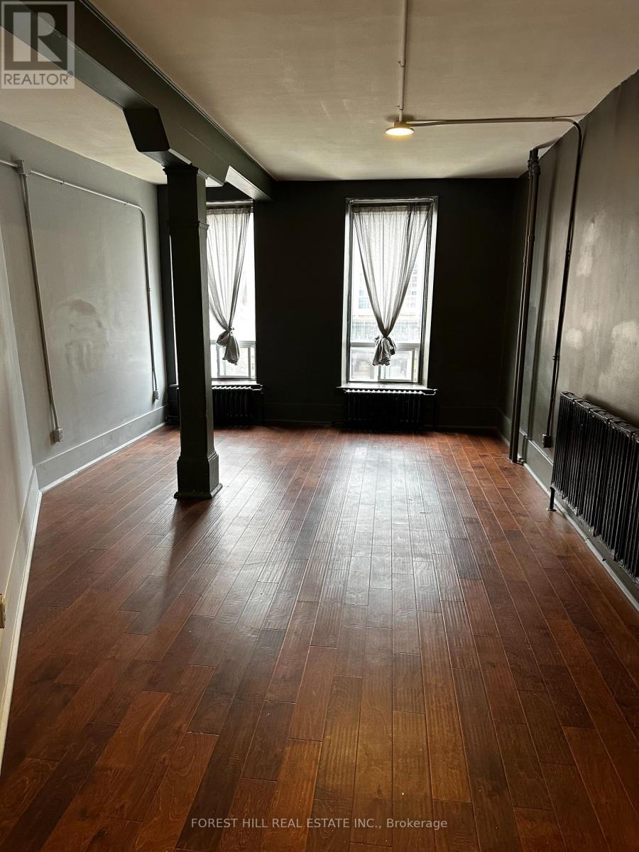 A room with wooden floors and two windows.