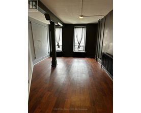 A room with wooden floors and two windows.