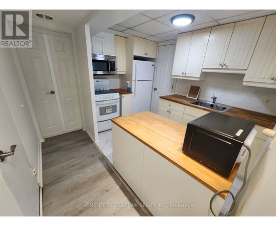 A kitchen with a microwave, oven, and refrigerator.