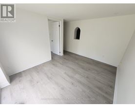 A room with a wooden floor and a small arched window.