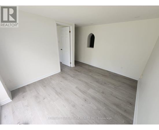 A room with a wooden floor and a small arched window.