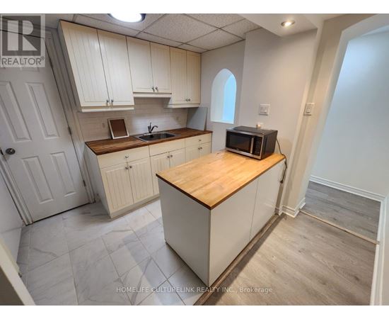 A kitchen with white cabinets and a wooden island.