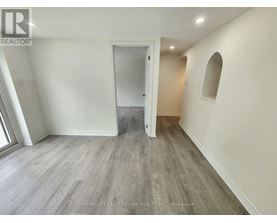 A spacious room with a doorway leading to another room.