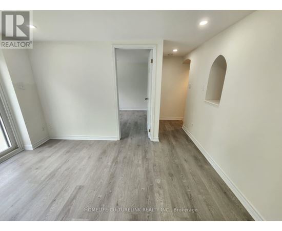 A spacious room with a doorway leading to another room.