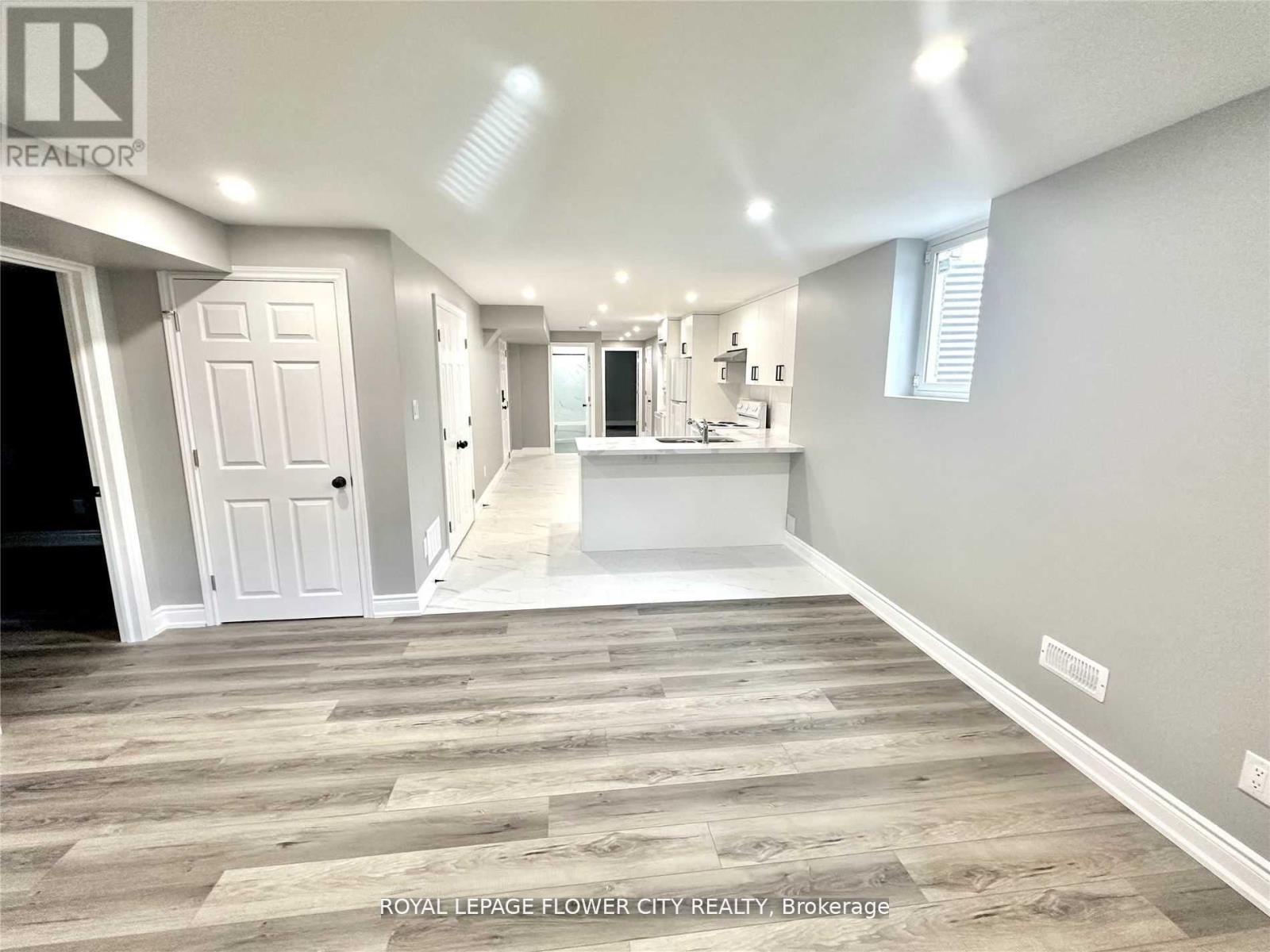 A spacious room with wooden flooring and white walls.