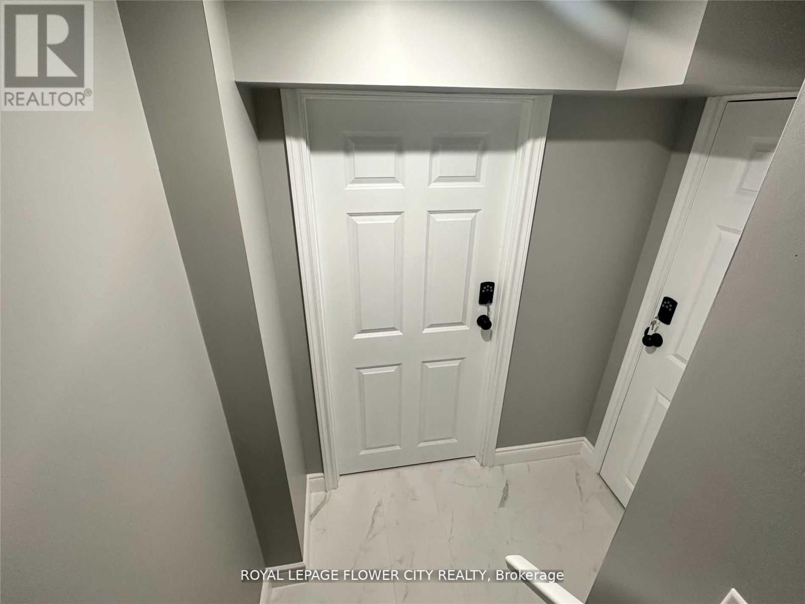 A white door in a hallway with a brokerage logo on the wall.