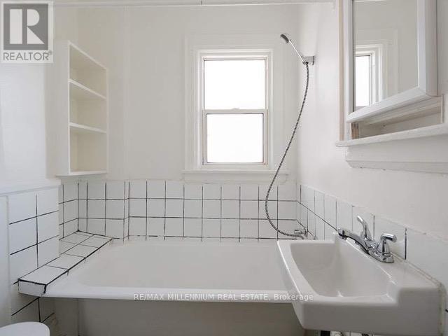 A white bathroom with a sink, toilet, and window.