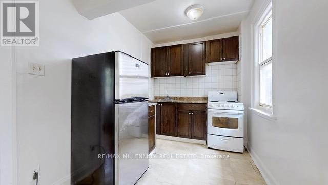 A kitchen with a black refrigerator, white oven and brown cabinets.