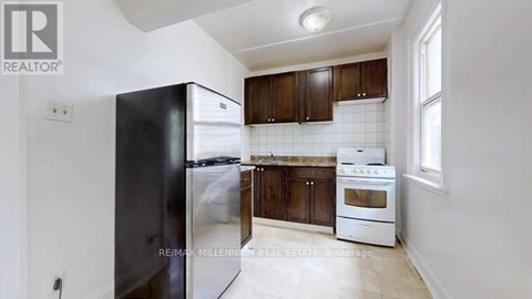 A kitchen with a black refrigerator, white oven and brown cabinets.