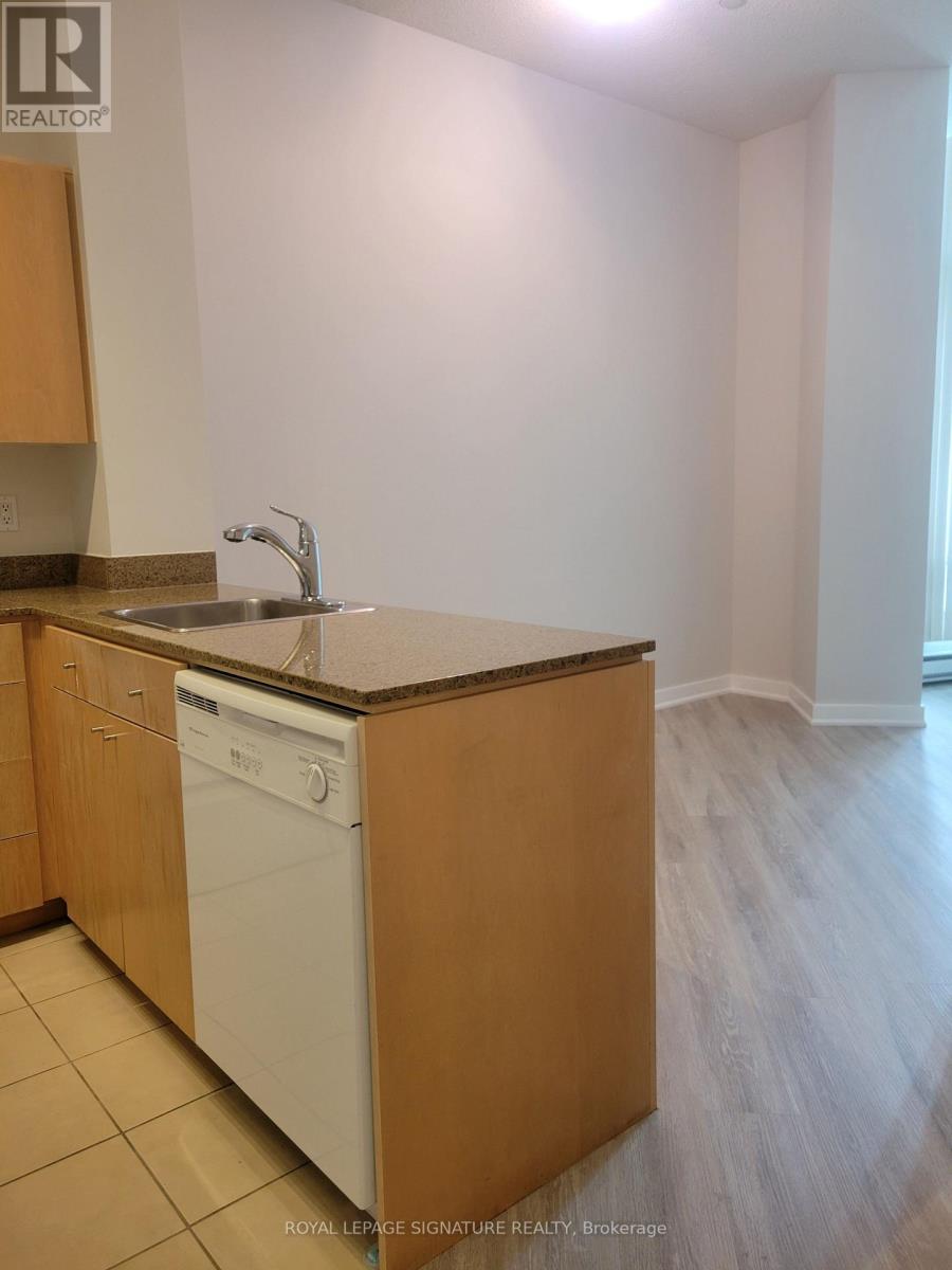 A kitchen with a white dishwasher and wooden cabinets.