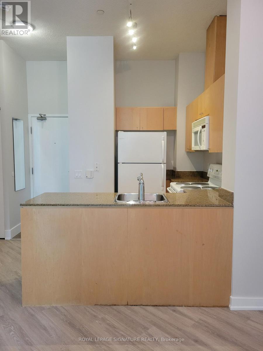 A kitchen with a white fridge and wooden island.