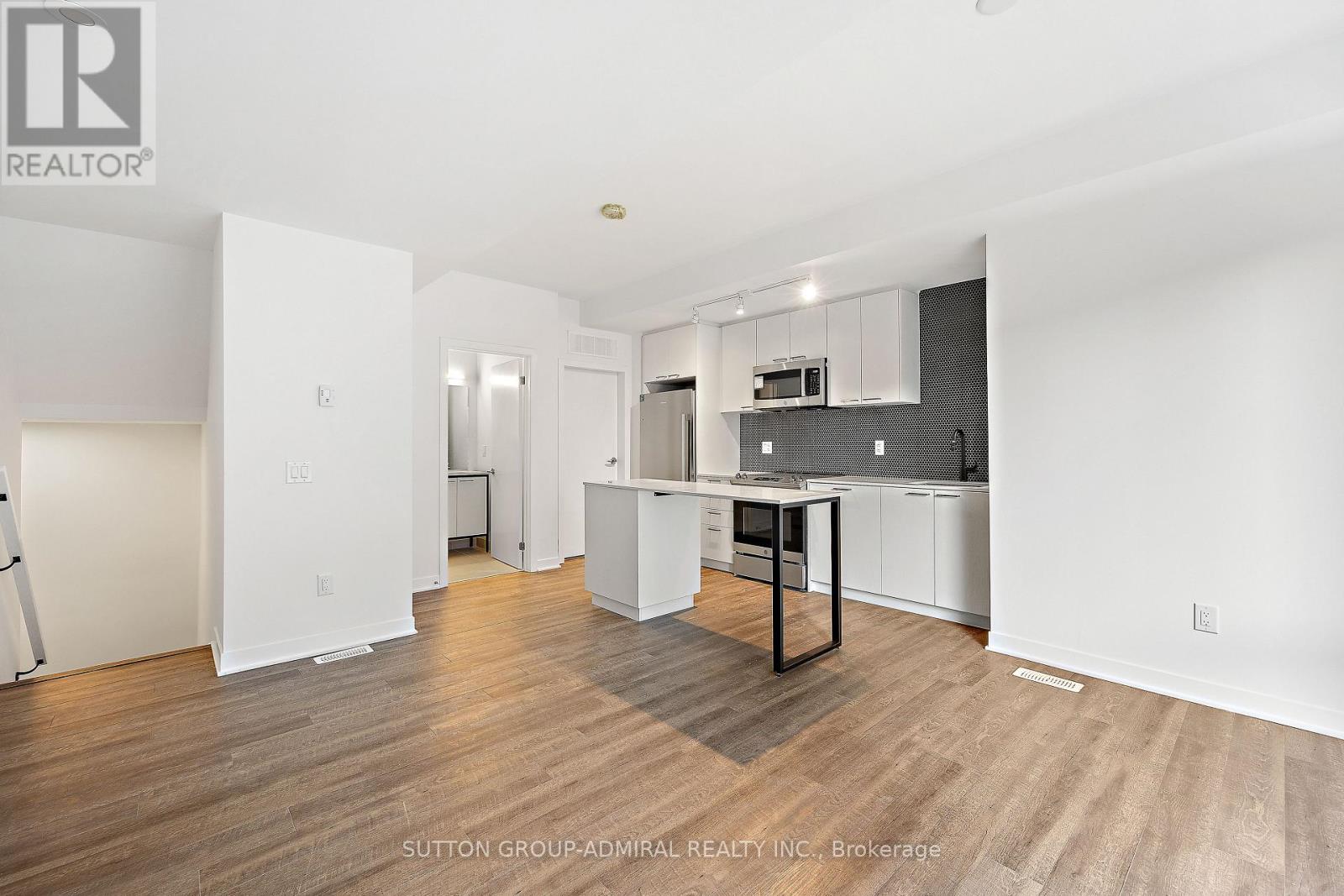 A spacious kitchen with white cabinets and a wooden floor.