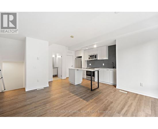 A spacious kitchen with white cabinets and a wooden floor.