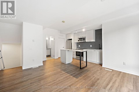 A spacious kitchen with white cabinets and a wooden floor.