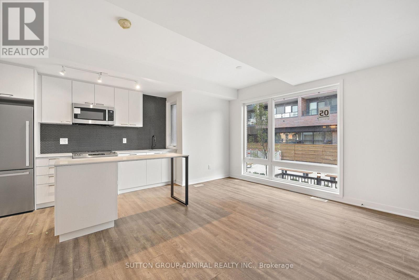 A modern kitchen with a refrigerator, microwave, and oven.