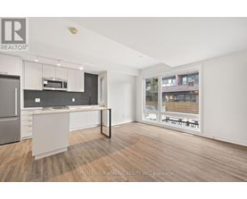 A modern kitchen with a refrigerator, microwave, and oven.