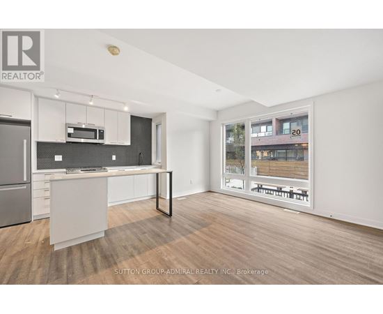 A modern kitchen with a refrigerator, microwave, and oven.