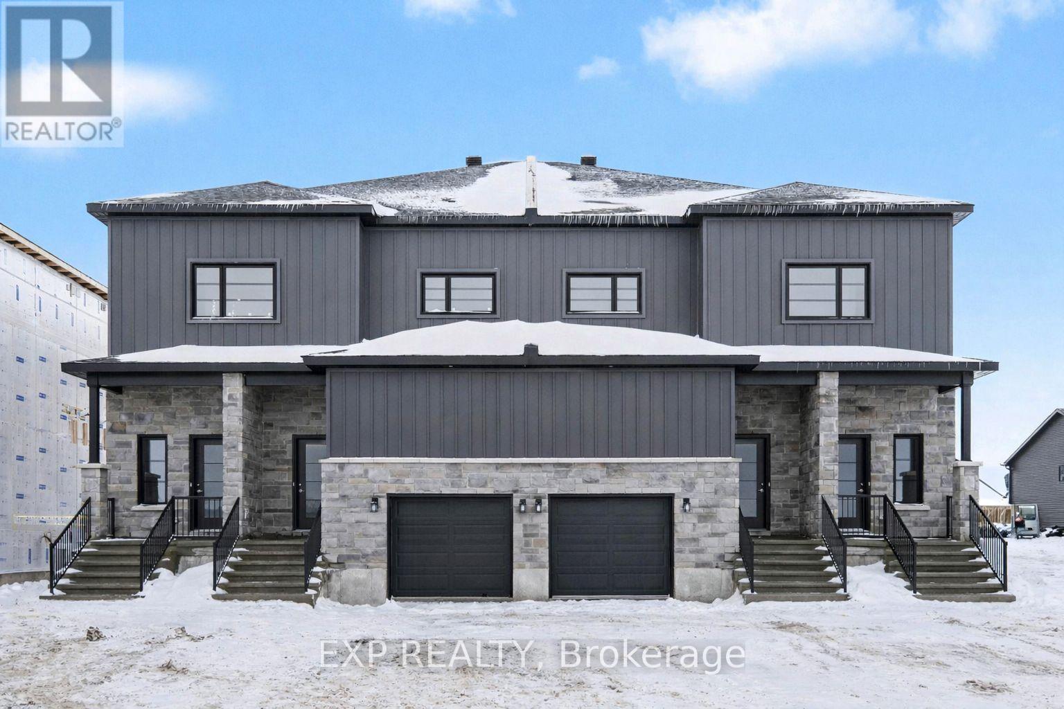 A large house with a grey roof and a stone facade is surrounded by snow.