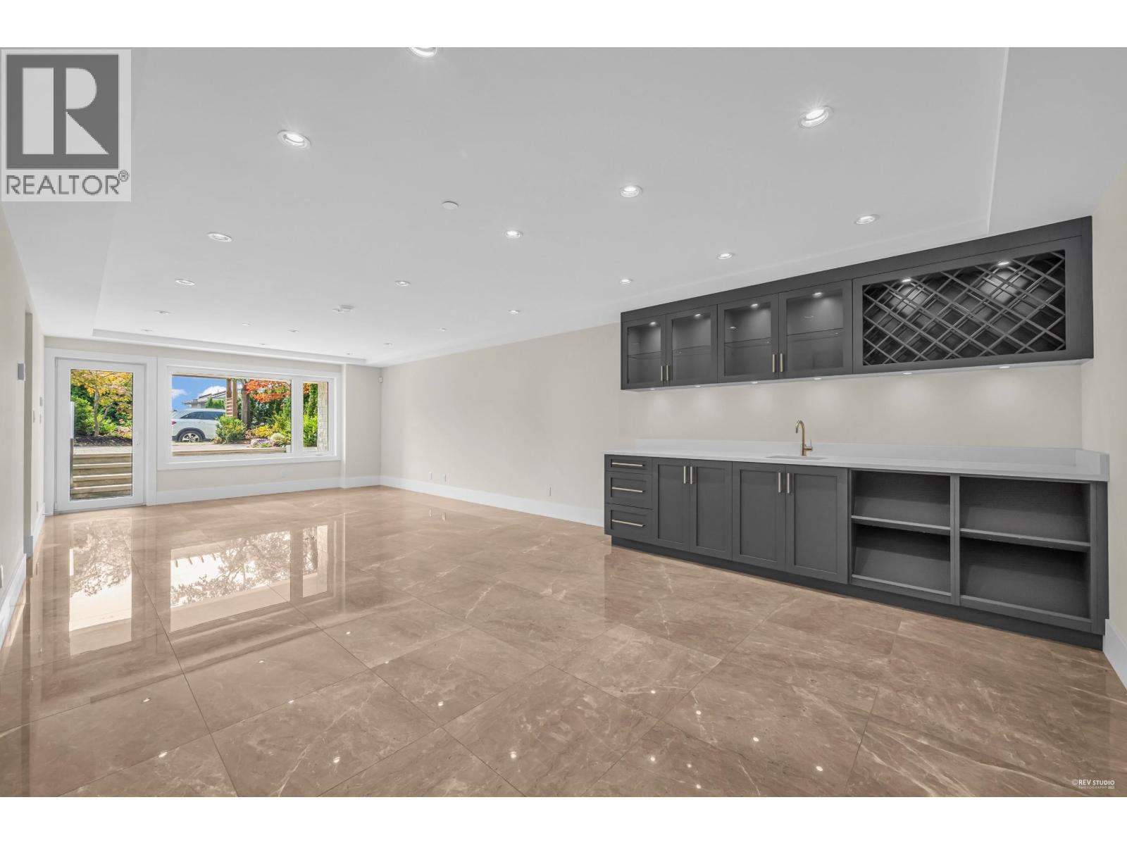 A spacious room with a marble floor and a large window overlooking a garden.