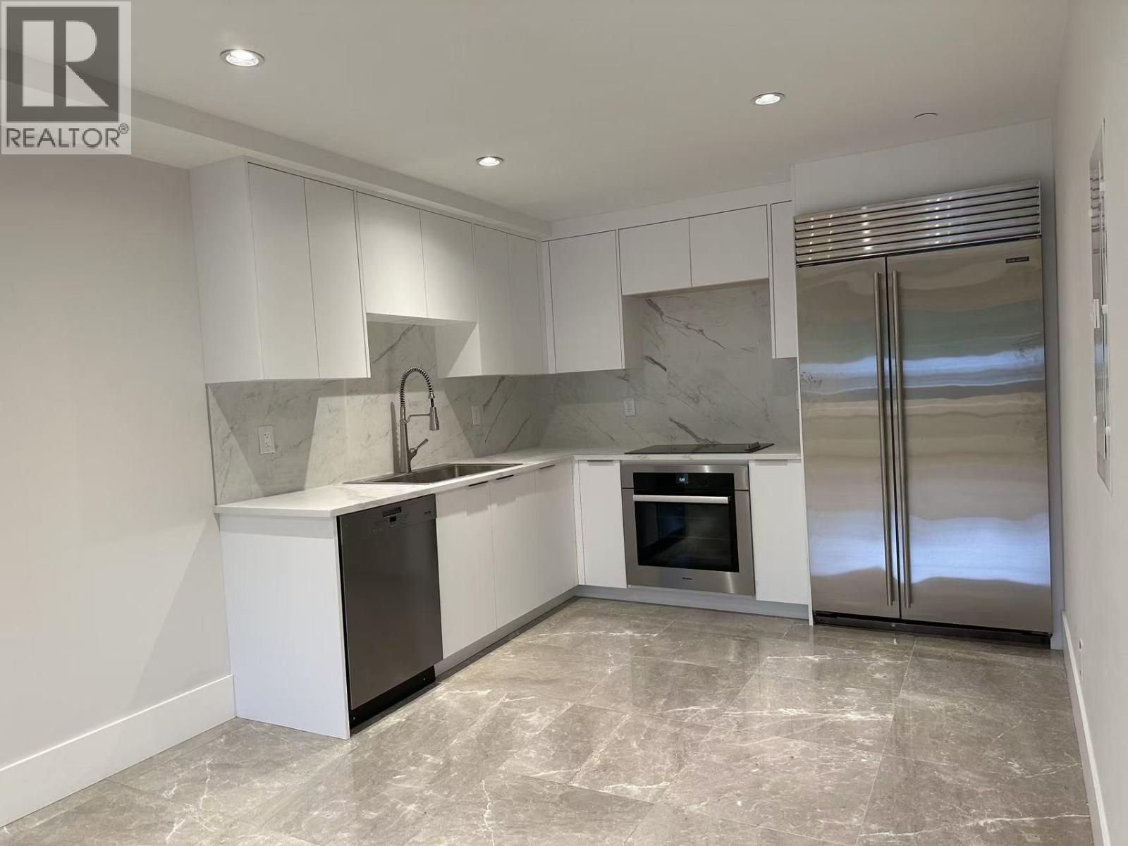 A modern kitchen with a marble backsplash and stainless steel appliances.