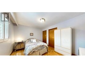 A bedroom with a bed, nightstand, and a window with blinds.