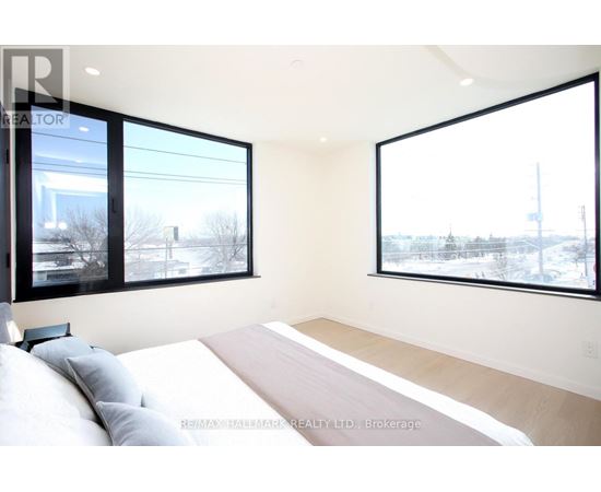 A bedroom with a large bed and two windows.