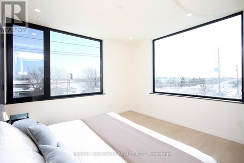 A bedroom with a large bed and two windows.