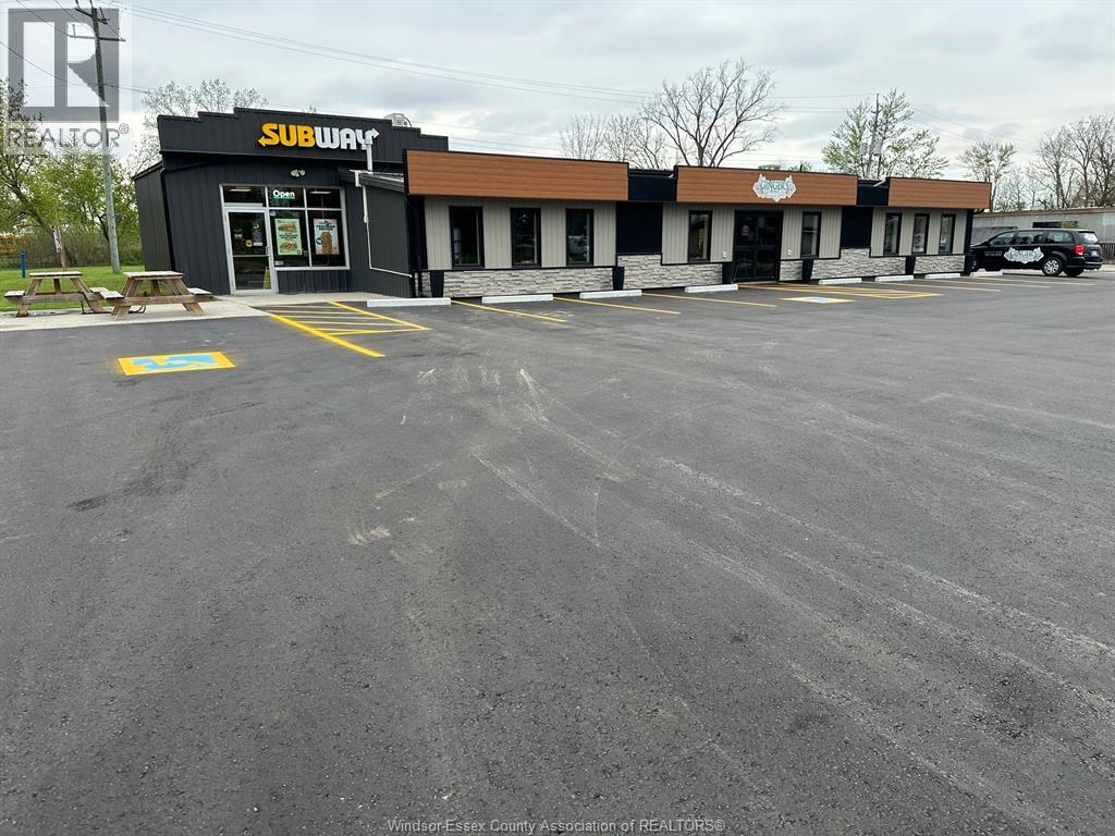 A Subway restaurant with a parking lot in front.