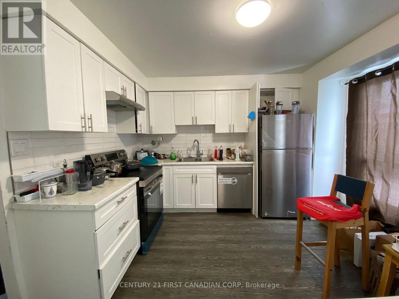 A kitchen with white cabinets and a stainless steel refrigerator.