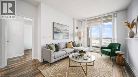 A living room with a grey couch, a green chair, a coffee table, and a painting on the wall.