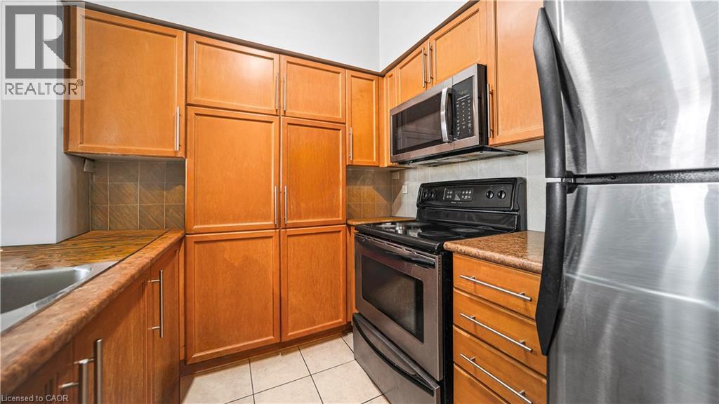 A kitchen with wooden cabinets and a stainless steel refrigerator.