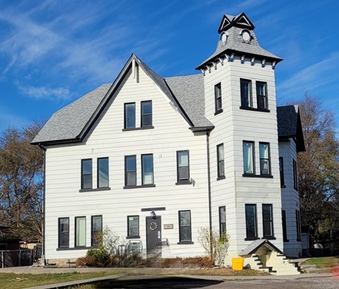 A white house with a black roof and a tower with a black and white striped roof.