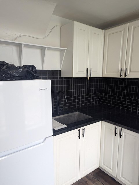A kitchen with white cabinets and a black counter.