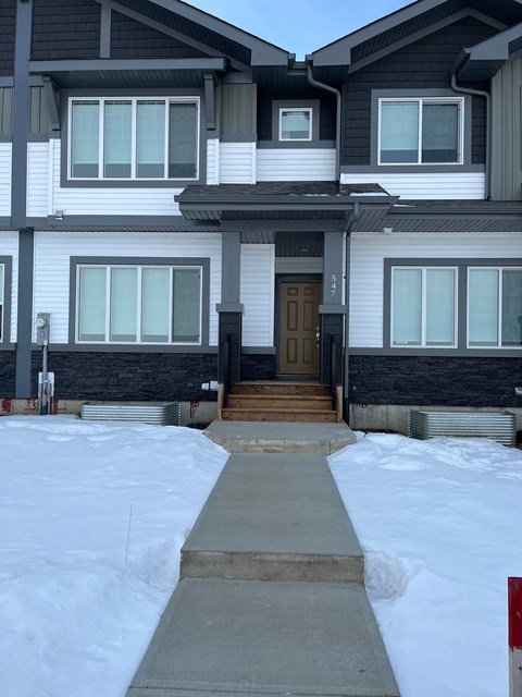 A house with a brown door and a snow-covered ground.