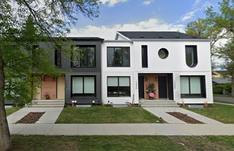 A modern two story house with a black roof and white walls.