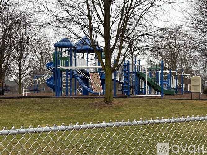 A playground with a blue slide and a white fence.