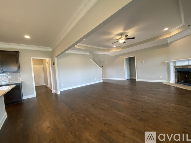 A spacious room with wooden floors and a ceiling fan.