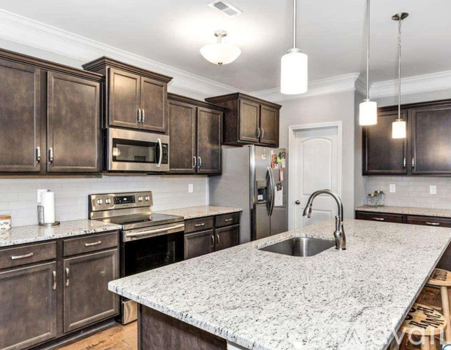 A kitchen with dark wood cabinets and a granite countertop.