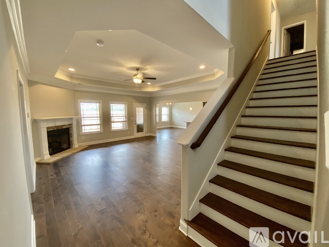 A spacious living room with a fireplace and a staircase leading to the upper level.