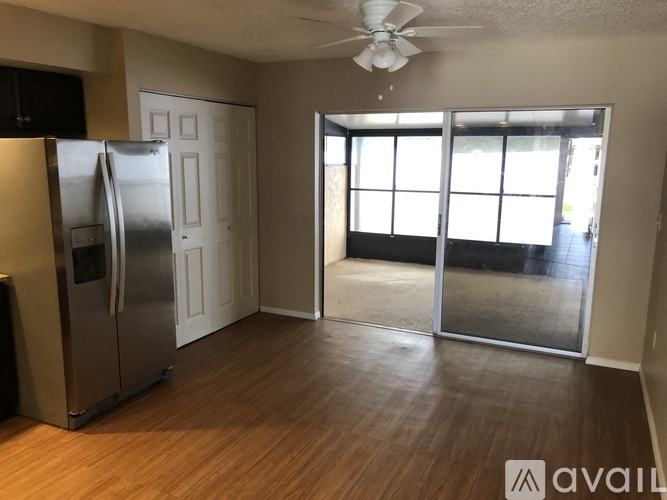 A kitchen with a refrigerator, a ceiling fan, and a sliding glass door leading to a balcony.