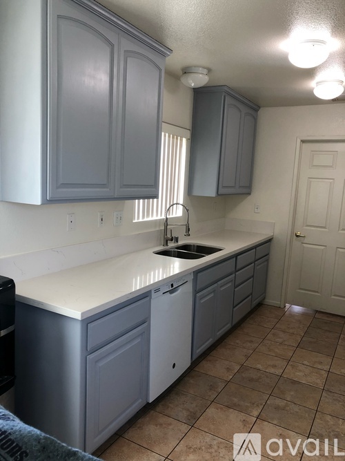 A kitchen with grey cabinets and a white counter top.