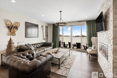 A living room with a black leather couch and a flat screen TV mounted on the wall.